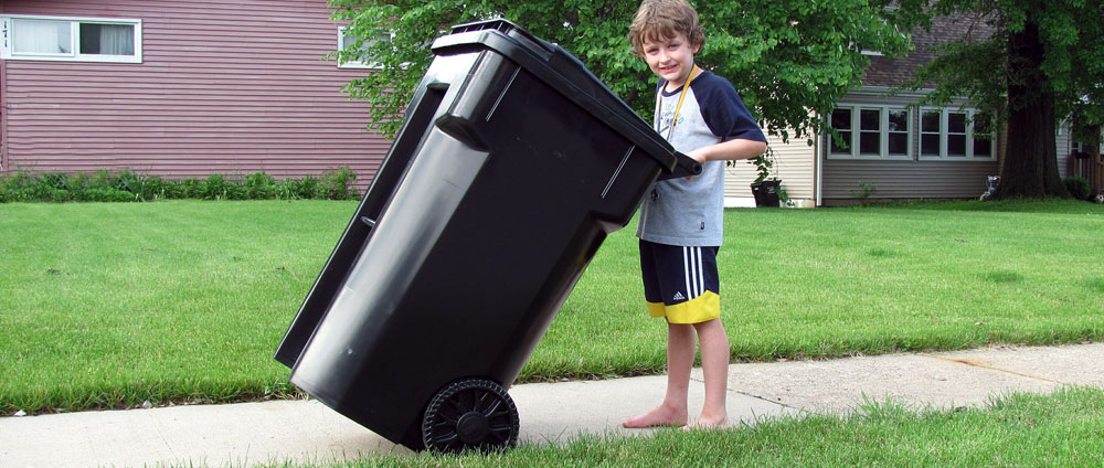 Image of a boy moving a garbage cart