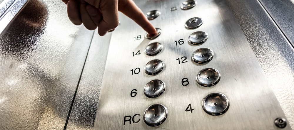 Image of finger pushing office elevator button