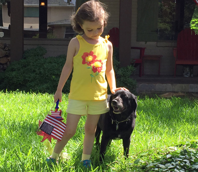 The backyard is the centerpiece of many children's lives. Dog and child in grass